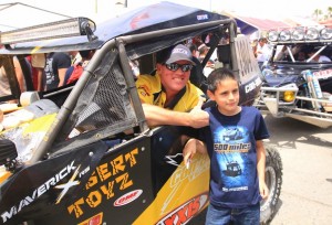 Cory Sappington and his No. 1904 Desert Toyz/ Can-Am Maverick 1000R X rs pose with a young fan at the starting line of the 40th annual Baja 500 in Mexico.